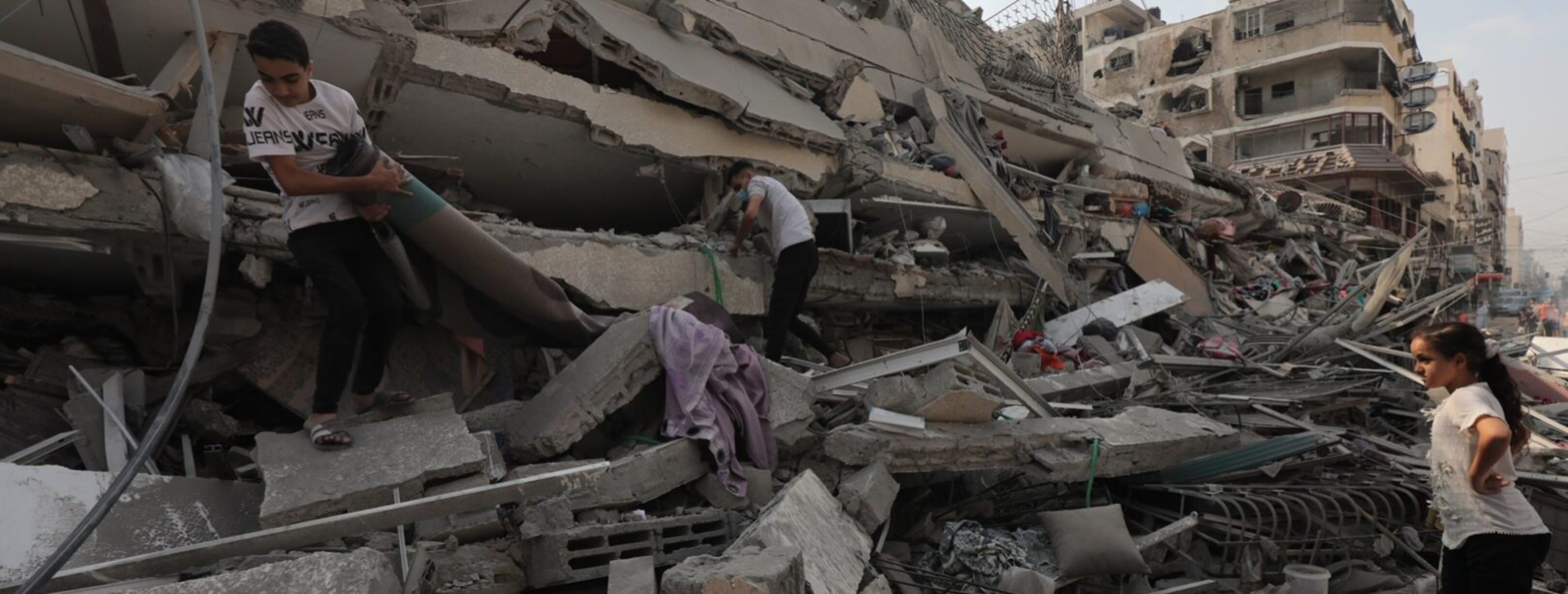 Palestinians inspect the ruins of Aklouk Tower destroyed in Israeli airstrikes in Gaza City